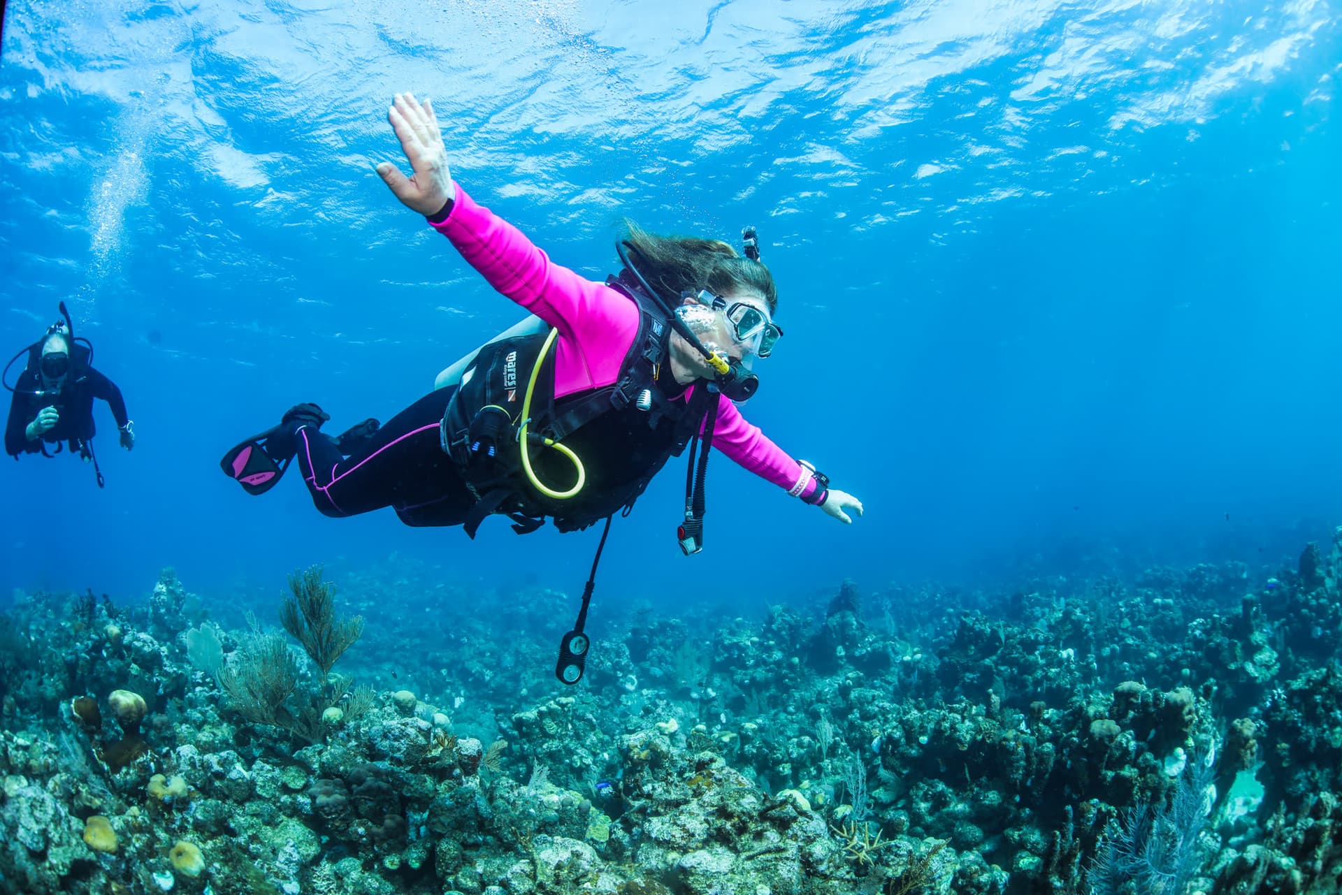 A diver gliding over the reef in clear water, West End Roatan