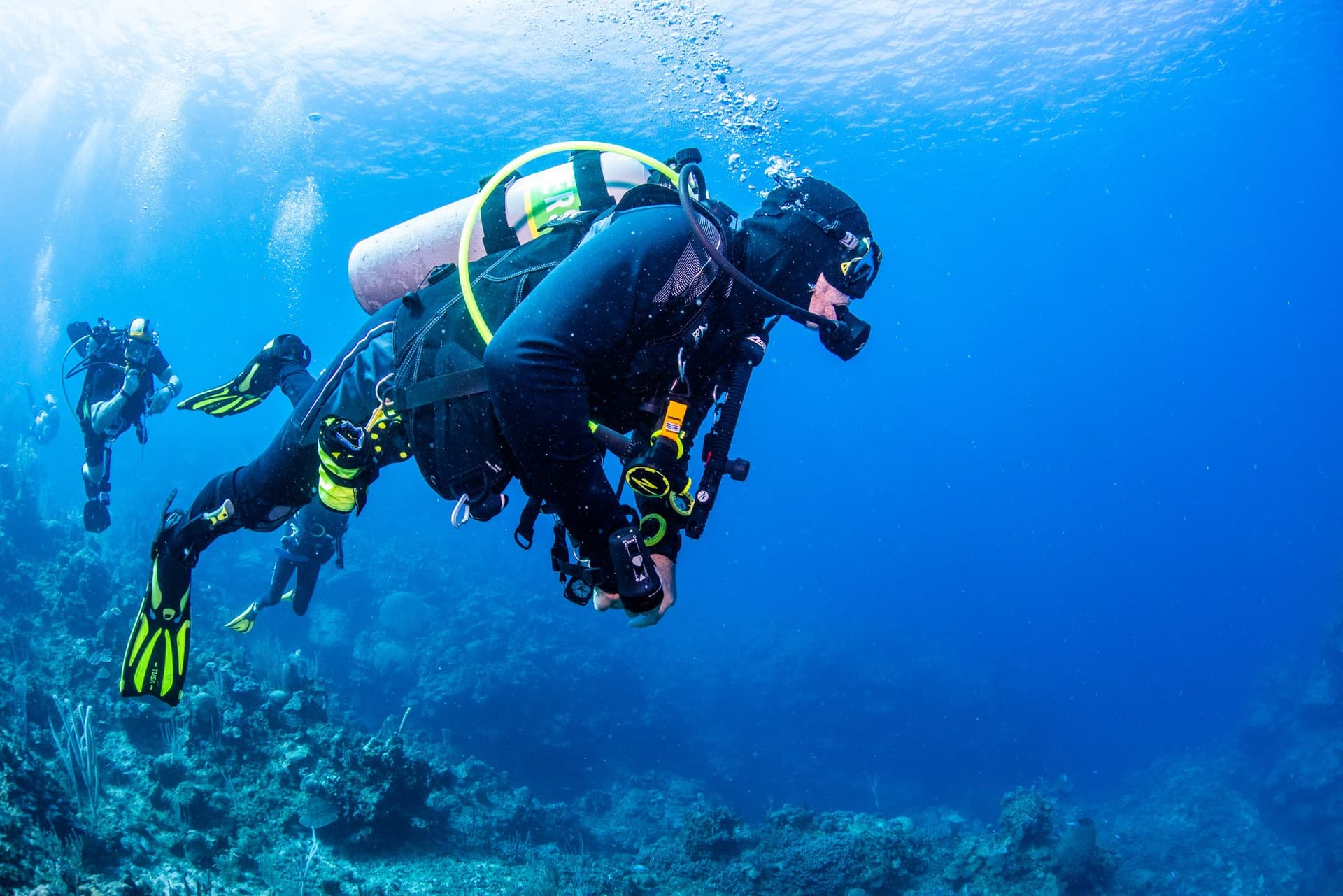 Divers gliding over the reef wall off West End, Roatan