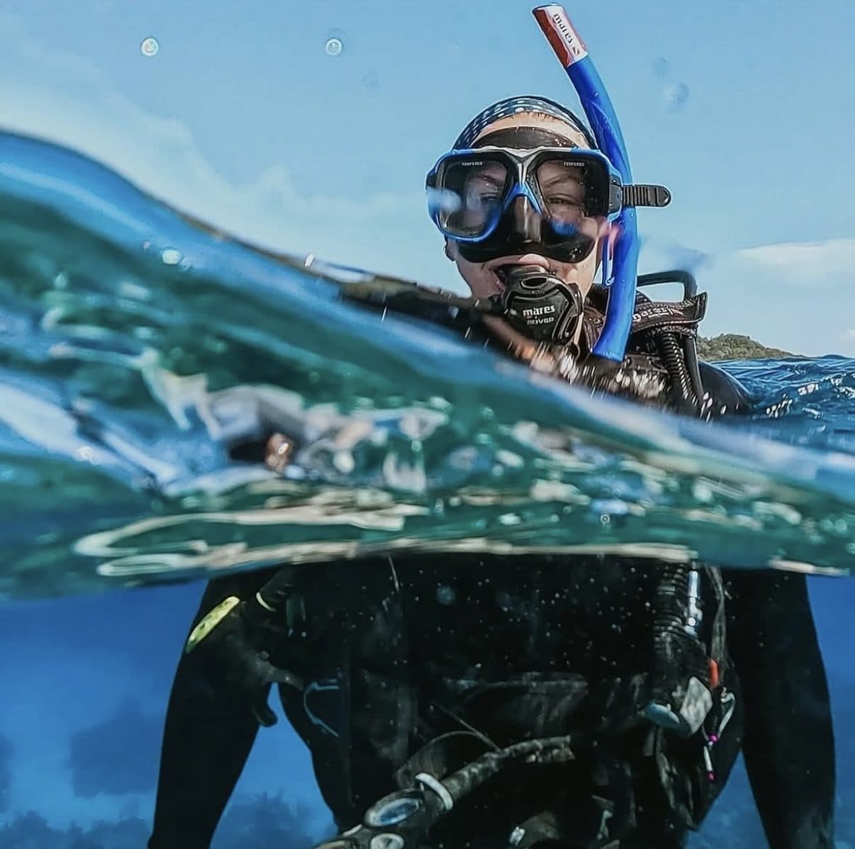 A snorkeler at the surface, half above and half below the water
